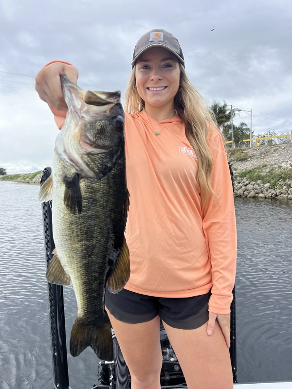 Woman angler holding a largemouth bass while fishing a canal