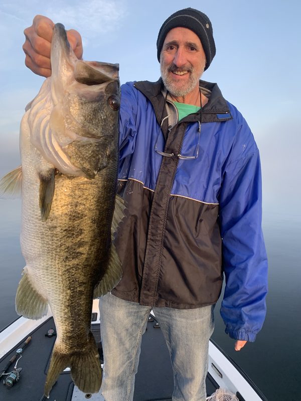 Angler holding a very large largemouth bass on a foggy, windless morning, Winter Haven Chain of Lakes