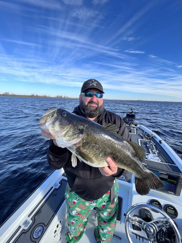 Angler holding a heavy winter largemouth bass across both hands on a bass boat