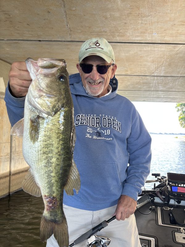 Angler under a boat canopy holding a large largemouth bass late in the day, Winter Haven Chain of Lakes