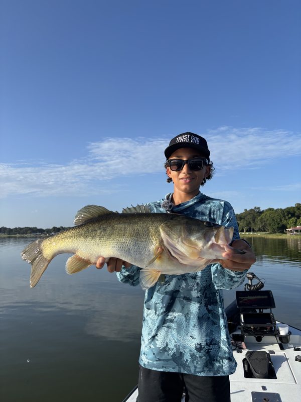 Teenage angler holding a largemouth bass horizontally on a summer guided trip, Winter Haven Chain of Lakes