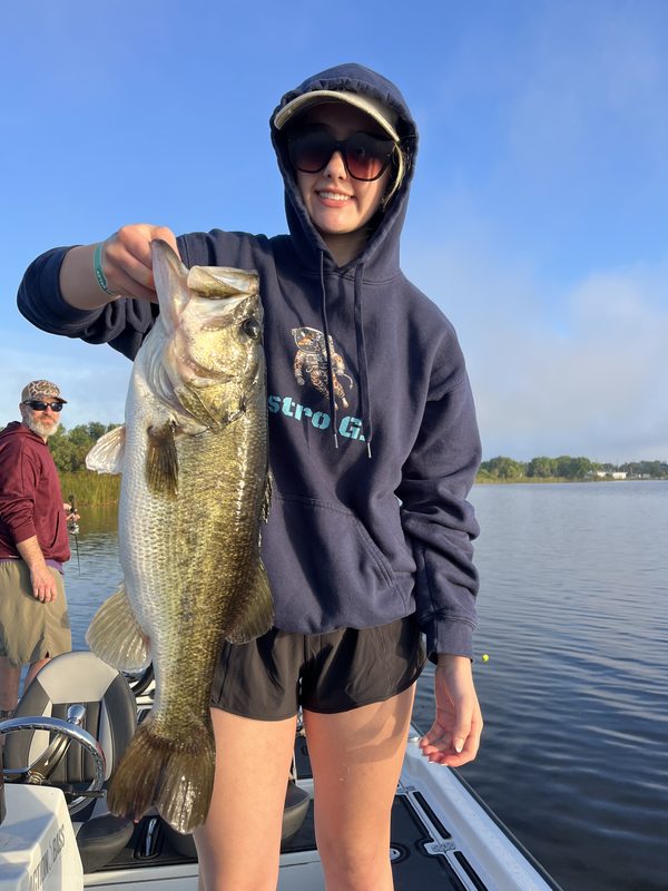 Teenage girl holding a largemouth bass by the jaw on a guided fishing charter, Winter Haven Chain of Lakes
