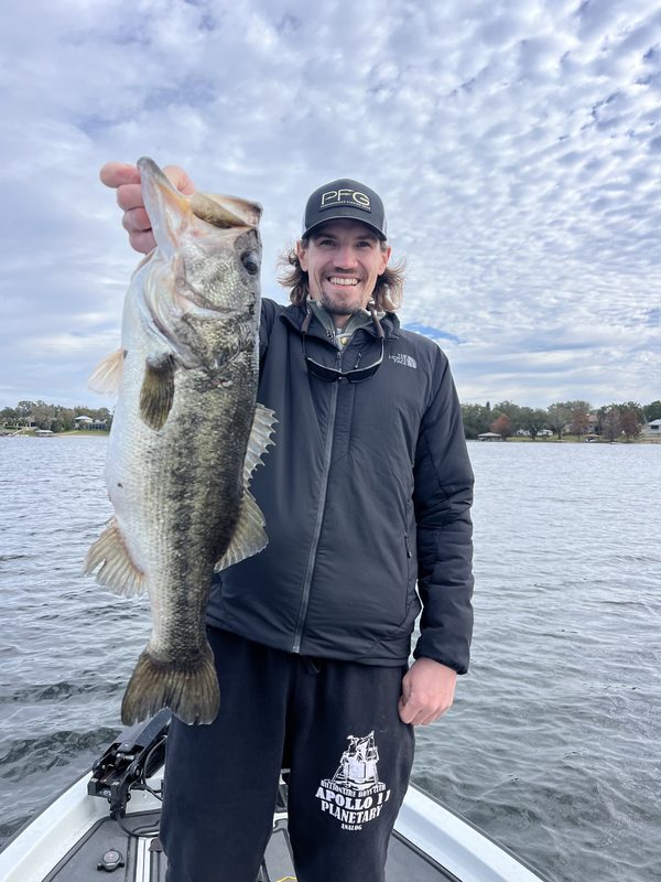 Angler in a jacket holding a large largemouth bass under a mackerel sky, Winter Haven Chain of Lakes