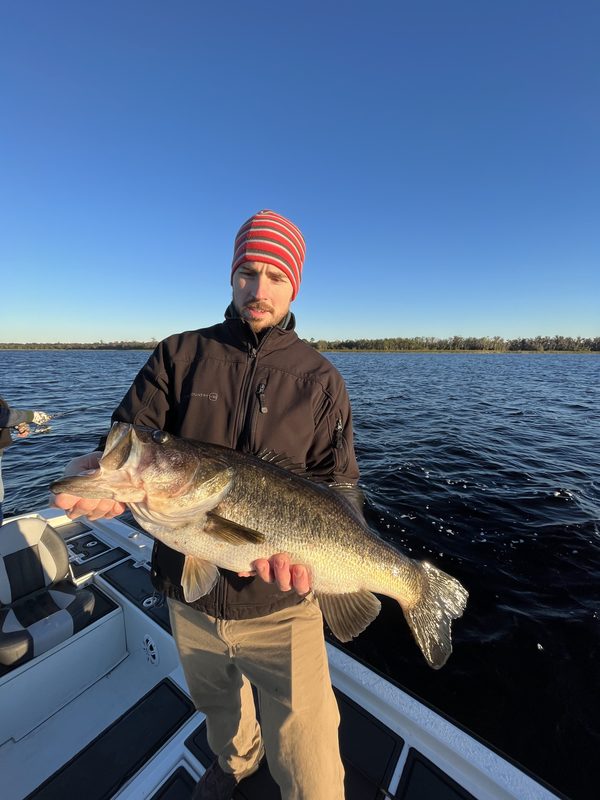 Angler in a knit cap holding a large largemouth bass on a cold winter morning, Winter Haven Chain of Lakes